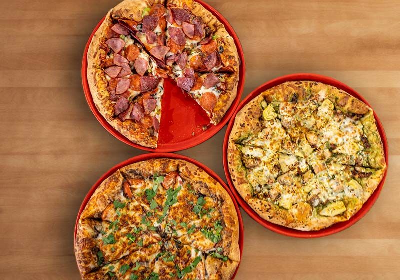 Three assorted Pizza Port pizzas on red trays